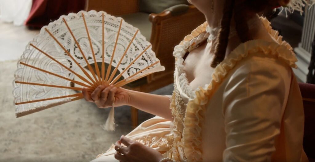 Woman in Regency dress holding a lace fan